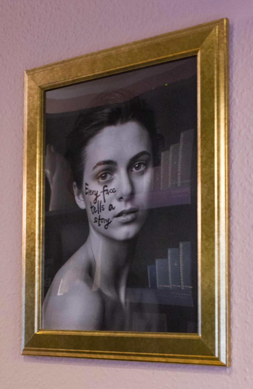 Bild im Rahmen mit abgebildeter Frau, auf Gesicht geschrieben „Every face tells a story“